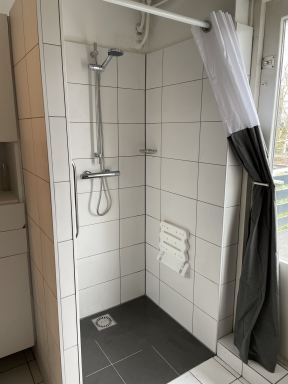 Badkamer aanpassing in Nuenen. Om spatwater tegen te gaan in de badkamer is er gekozen voor een douchegordijn. Dankzij een goede afschot in het tegelwerk was een dorpel (gelukkig) niet nodig zodat ook mensen die slechter ter been zijn gemakkelijk onder de