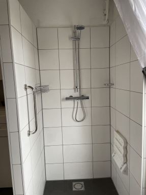 Badkamer aanpassing in Nuenen. De douche is voorzien van een opklapbaar douche zitje en een beugel aan de muur om je aan vast te houden.